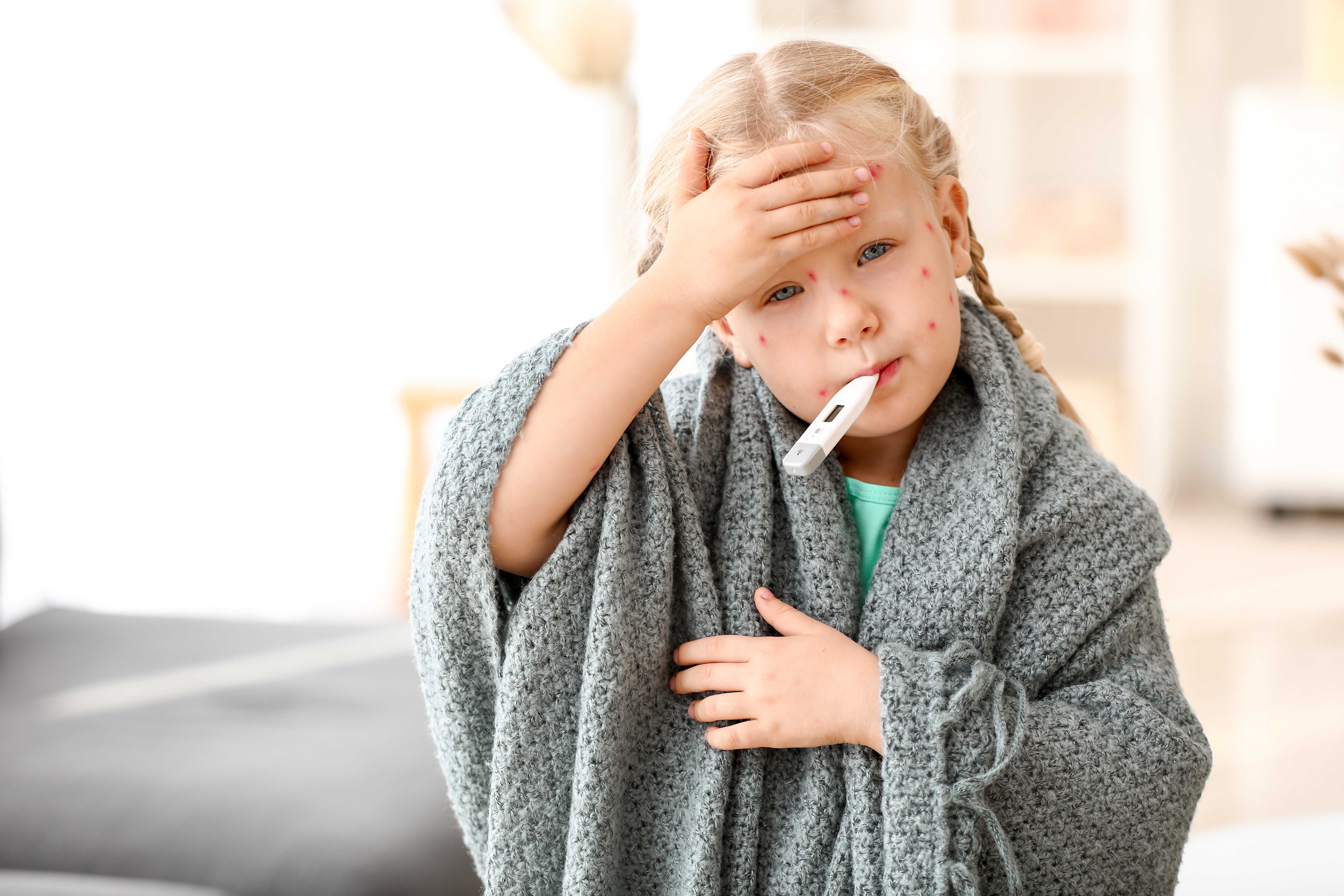 A child holding her forehead taking her temperature